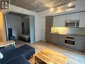 Toronto (Kensington-Chinatown) condo for rent - A modern kitchen with a blue sofa and wooden coffee table.