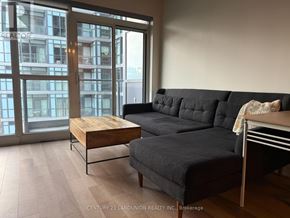 Toronto (Kensington-Chinatown) condo for rent - A grey couch with a wooden table in front of a glass door.