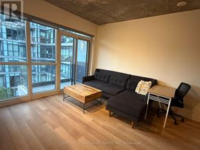 Toronto (Kensington-Chinatown) condo for rent - A living room with a black couch, a coffee table, and a chair.