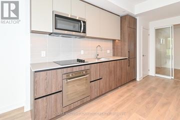 Toronto (South Riverdale) condo for rent - A kitchen with wooden cabinets and a microwave above the stove.