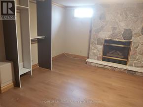 Oshawa (Eastdale) apartment for rent - A room with a stone fireplace and wooden floors.