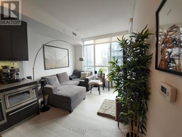 Toronto (Waterfront Communities) condo for rent - A living room with a grey couch and a large plant.