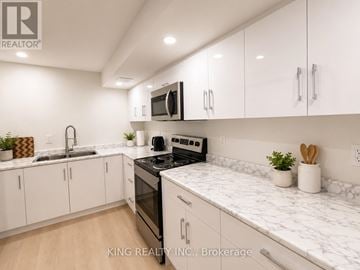 Kitchener duplex for rent - A modern kitchen with white cabinets and marble countertops.