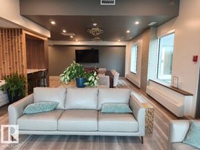 Edmonton apartment for rent - A living room with a white couch and a flat screen TV mounted on the wall.