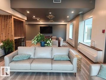 Edmonton apartment for rent - A living room with a white couch and a flat screen TV mounted on the wall.