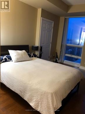 Toronto (Bay Street Corridor) condo for rent - A bedroom with a white bedspread and a black headboard.