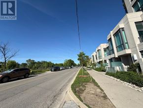 Toronto (Thorncliffe Park) condo for rent - A street view with a car parked on the side of the road and modern buildings on the right.