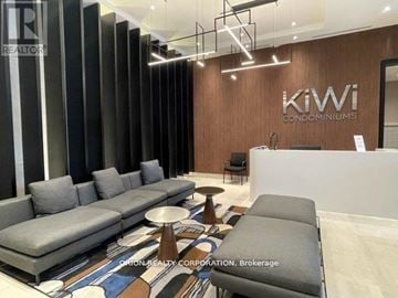 Hamilton (Beasley) condo for rent - A modern living room with a grey sofa and a wooden wall with the word "kiwi" written on it.