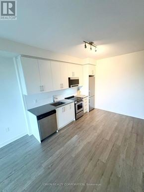 Hamilton (Beasley) condo for rent - A kitchen with white cabinets and a wooden floor.