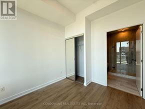 Toronto (Bayview Village) condo for rent - A room with a white wall and a wooden floor with a door on the left and a glass door on the right.