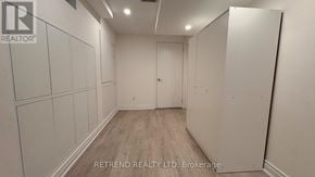 Vaughan (Patterson) apartment for rent - A room with white walls and wooden flooring, with a door on the right side.