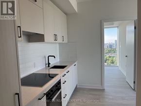 Toronto (Banbury-Don Mills) condo for rent - A kitchen with white cabinets and a black stove top.