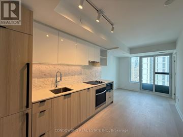 Toronto (Church-Yonge Corridor) condo for rent - A modern kitchen with wooden cabinets and a marble backsplash.