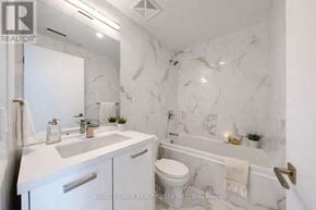 Toronto (Moss Park) condo for rent - A white bathroom with marble walls and a toilet.