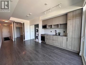 Toronto (Waterfront Communities) condo for rent - A spacious kitchen with wooden cabinets and a washing machine.