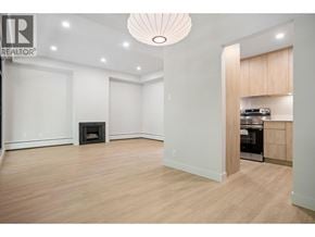 Vancouver townhouse for rent - A large, empty room with a fireplace and a kitchen area in the background.
