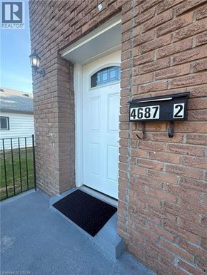 Niagara Falls apartment for rent - A white door is on the side of a brick building with a black sign above it that says 4687 2.