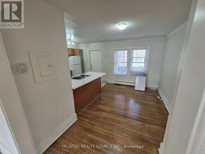 Windsor multi-family for rent - A room with wooden floors and white walls, with a window and a door visible.