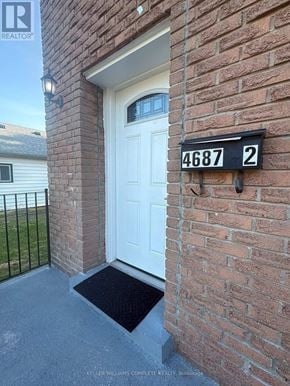 Niagara Falls (Cherrywood) multi-family for rent - A white door is on the front of a brick building with a black mailbox that has the number 4687 on it.