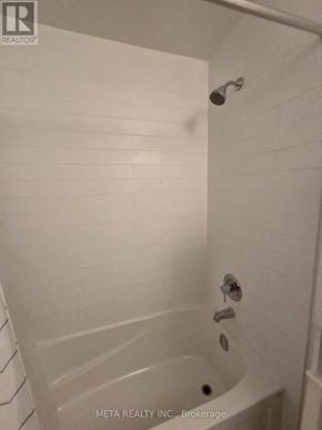 Toronto (Niagara) condo for rent - A white tiled shower with a drain in the middle.