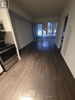 Toronto (Niagara) condo for rent - A spacious room with wooden flooring and a large window with curtains.