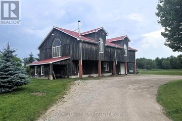 Shelburne apartment for rent - A large wooden barn with a red roof and a gravel driveway in front.