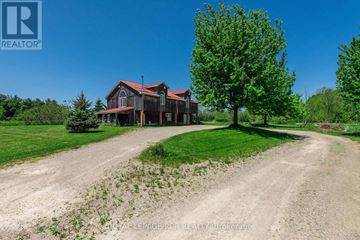 Shelburne apartment for rent - A large house with a red roof is situated on a grassy area with a dirt road leading to it.