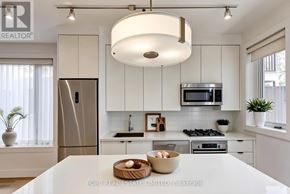 Toronto (Palmerston-Little Italy) multi-family for rent - A modern kitchen with a refrigerator, microwave, oven, and a bowl of fruit on the counter.