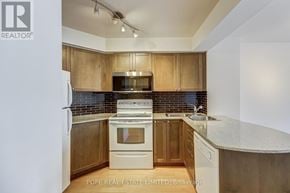 Toronto (Bay Street Corridor) condo for rent - A kitchen with wooden cabinets and a white refrigerator.