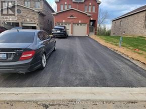 Kawartha Lakes (Lindsay) apartment for rent - A car is parked on a driveway in front of a brick house.