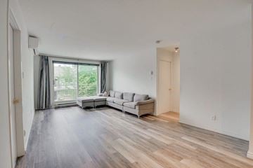 Gatineau (Hull) condo for rent - A spacious living room with a grey sofa and a large window.