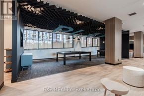 Vaughan (Beverley Glen) condo for rent - A modern office space with a large window, wooden floors, and a variety of furniture including a sofa, chairs, and a desk.
