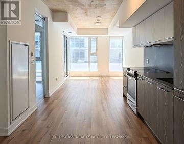 Toronto (South Riverdale) condo for rent - A spacious kitchen with wooden floors and modern appliances.