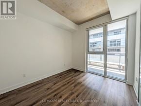 Toronto (South Riverdale) condo for rent - A room with wooden flooring and a sliding glass door leading to a balcony.