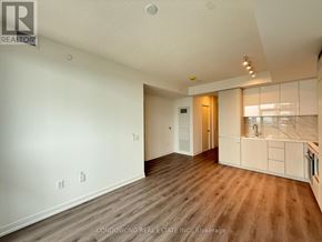 Vaughan (Vaughan Corporate Centre) condo for rent - A spacious room with wood flooring and a kitchen area in the background.