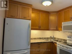Mississauga (Lakeview) apartment for rent - A kitchen with wooden cabinets and a white refrigerator.