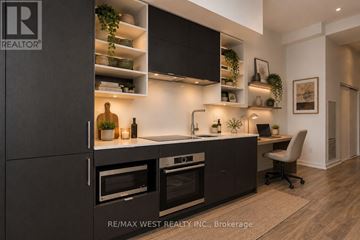 Toronto (Bay Street Corridor) condo for rent - A modern kitchen with dark cabinets and a black countertop.