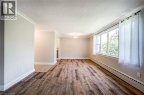 Burlington condo for rent - A spacious room with wooden flooring and a window with white curtains.