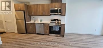 Kitchener condo for rent - A kitchen with wooden cabinets and stainless steel appliances.