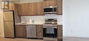 Kitchener condo for rent - A kitchen with a refrigerator, microwave, oven, and sink.