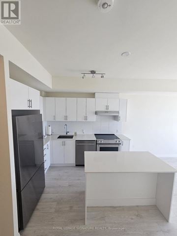 Vaughan (Vellore Village) condo for rent - A modern kitchen with white cabinets and a black refrigerator.