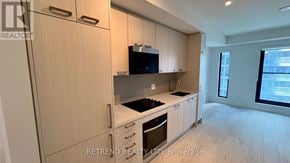 Toronto (Mount Pleasant West) condo for rent - A kitchen with wooden cabinets and a black microwave above the stove.