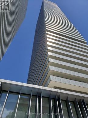 Toronto (Church-Yonge Corridor) condo for rent - A tall building with a glass facade stands next to a shorter building with a striped facade.