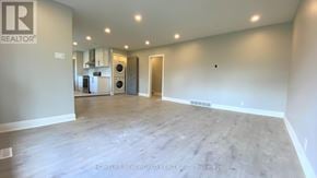Oshawa (Eastdale) apartment for rent - A spacious room with a logo on the wall and a doorway leading to another room.