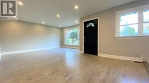 Oshawa (Eastdale) apartment for rent - A room with a black door and a window showing trees outside.