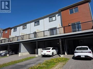 Barrie townhouse for rent - A white car is parked in the garage of a multi-story apartment building.