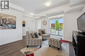 Kitchener townhouse for rent - A living room with a couch, chair, ottoman, and a painting on the wall.