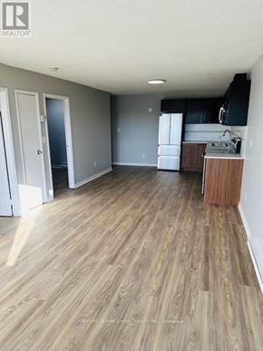 New Tecumseth (Alliston) multi-family for rent - A kitchen with a white fridge and black cabinets.