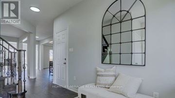 Clarington (Bowmanville) apartment for rent - A living room with a white couch and a mirror on the wall.