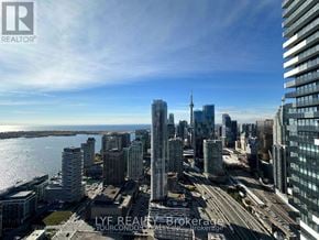 Toronto (Waterfront Communities) condo for rent - A cityscape with tall buildings and a body of water in the foreground.
